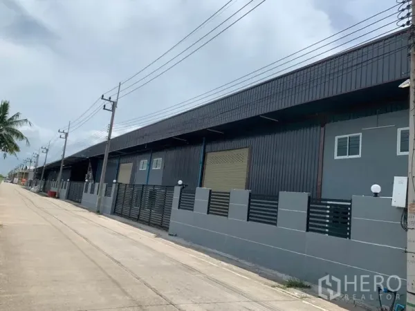工厂 出租在Khlong Luang, Pathum Thani - 孔龙銮工业区的现代工厂外立面，带卷闸门与安全围栏，临宽阔道路。