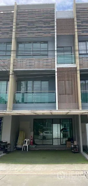 Townhouse for sale in Bueng Kum, Bangkok - Front elevation of a three-storey townhouse with gated carport and glass frontage.