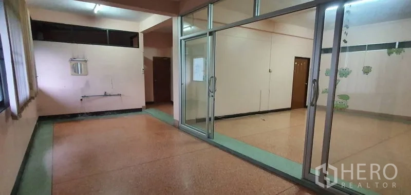 Warehouse for rent in Bang Kho Laem, Bangkok - Open area with sliding glass doors, terrazzo floor, and a small sink nook.