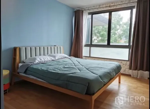 Condominium for rent in Khlong Toei, Bangkok - Primary bedroom with large window, blue accent wall, and garden views.