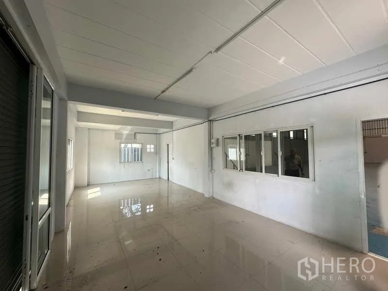 Warehouse for rent in Pathum Thani - Bright office room with tiled floors, windows and a sliding glass partition inside the warehouse.