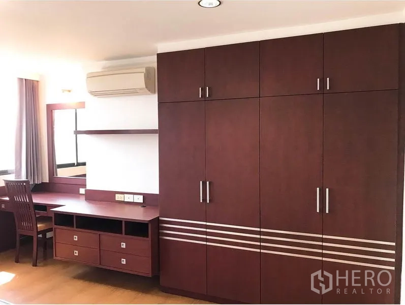 Condominium for rent or sale in Watthana, Bangkok - Bedroom storage with full-height wooden wardrobe, work desk, mirror and air conditioner.