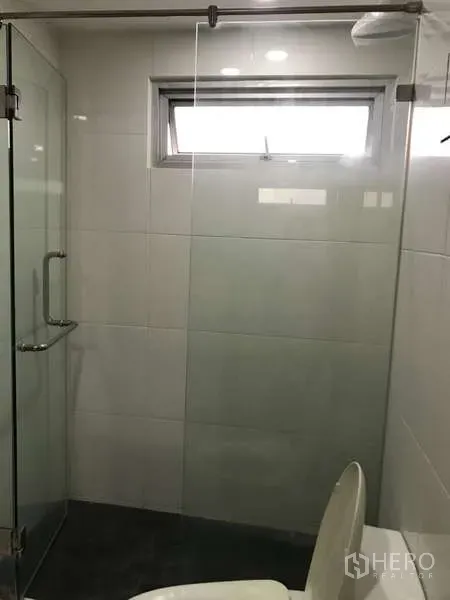 公寓 出售在Watthana, Bangkok - 现代浴室，玻璃淋浴间、白色瓷砖和小窗。