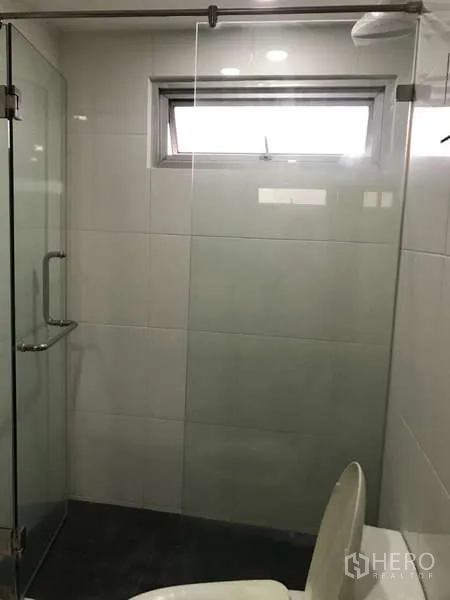 公寓 出售在Watthana, Bangkok - 现代浴室，玻璃淋浴间、白色瓷砖和小窗。