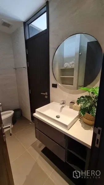 公寓 出租在Watthana, Bangkok - 浴室盥洗台，圆镜与储物柜设计。