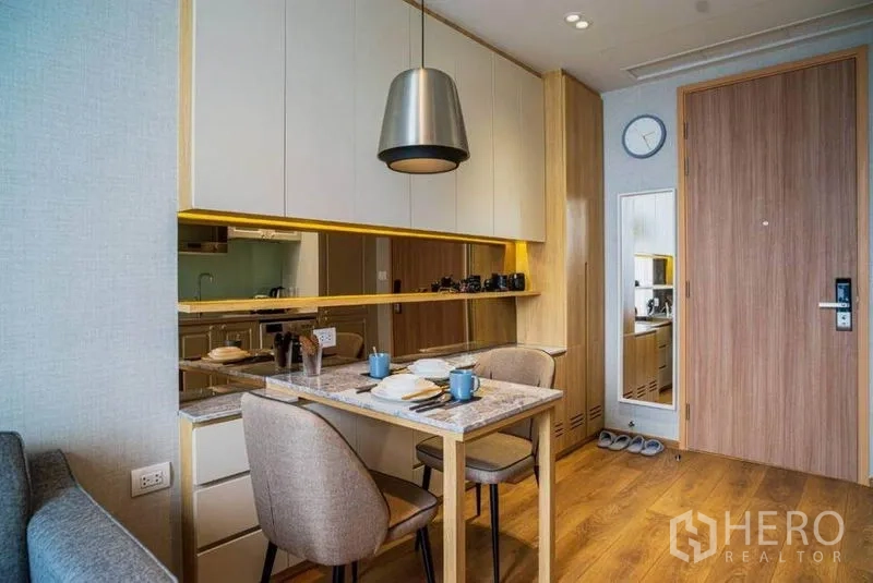 公寓 出租在Watthana, Bangkok - 温馨用餐角，带大理石餐桌、吊灯与镜面收纳柜。