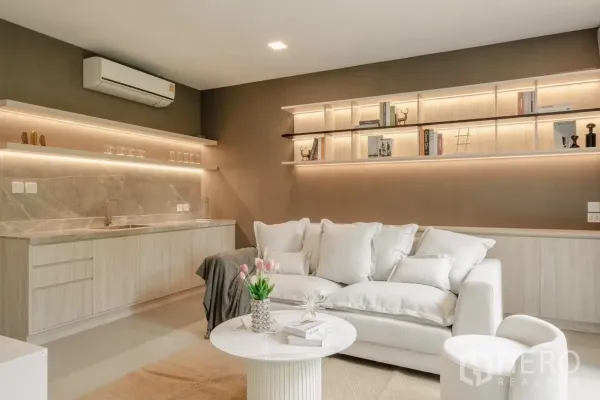 Detached House for rent in Saphan Sung, Bangkok - Family lounge with a pantry kitchenette, marble backsplash, LED‑lit floating shelves, and a plush sofa.