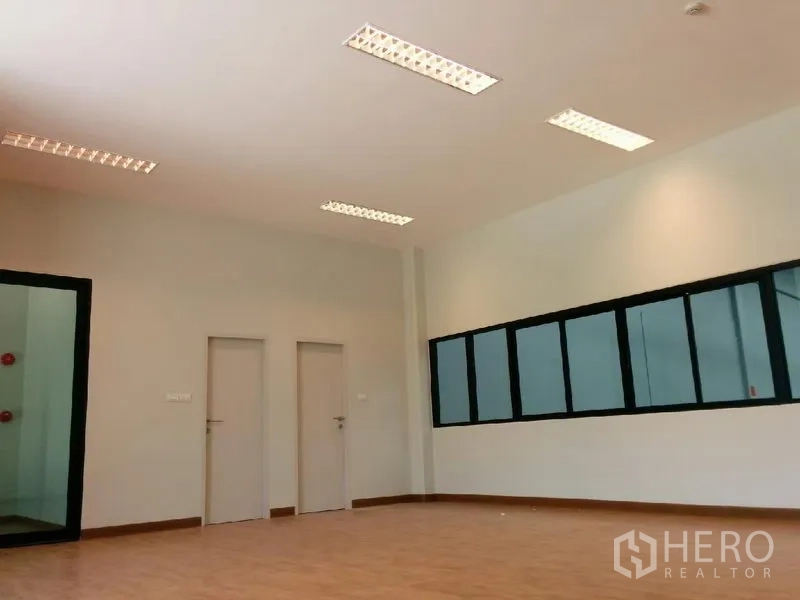 Factory for rent in Samut Prakan - Upper-level office room with wood flooring, internal windows, and doors.