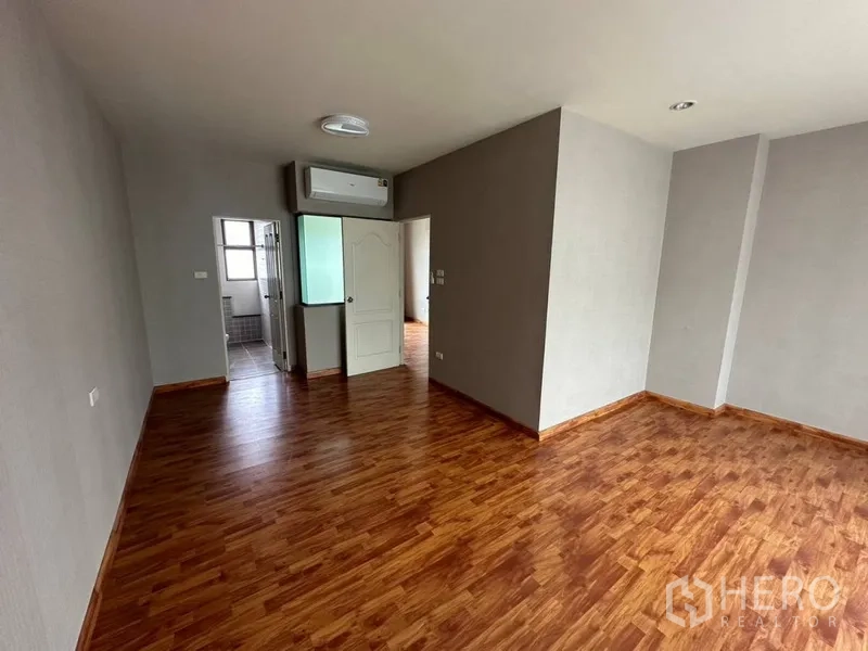 Townhouse for rent or sale in Phra Khanong, Bangkok - Spacious master bedroom with doorway to ensuite bathroom and wood floors.