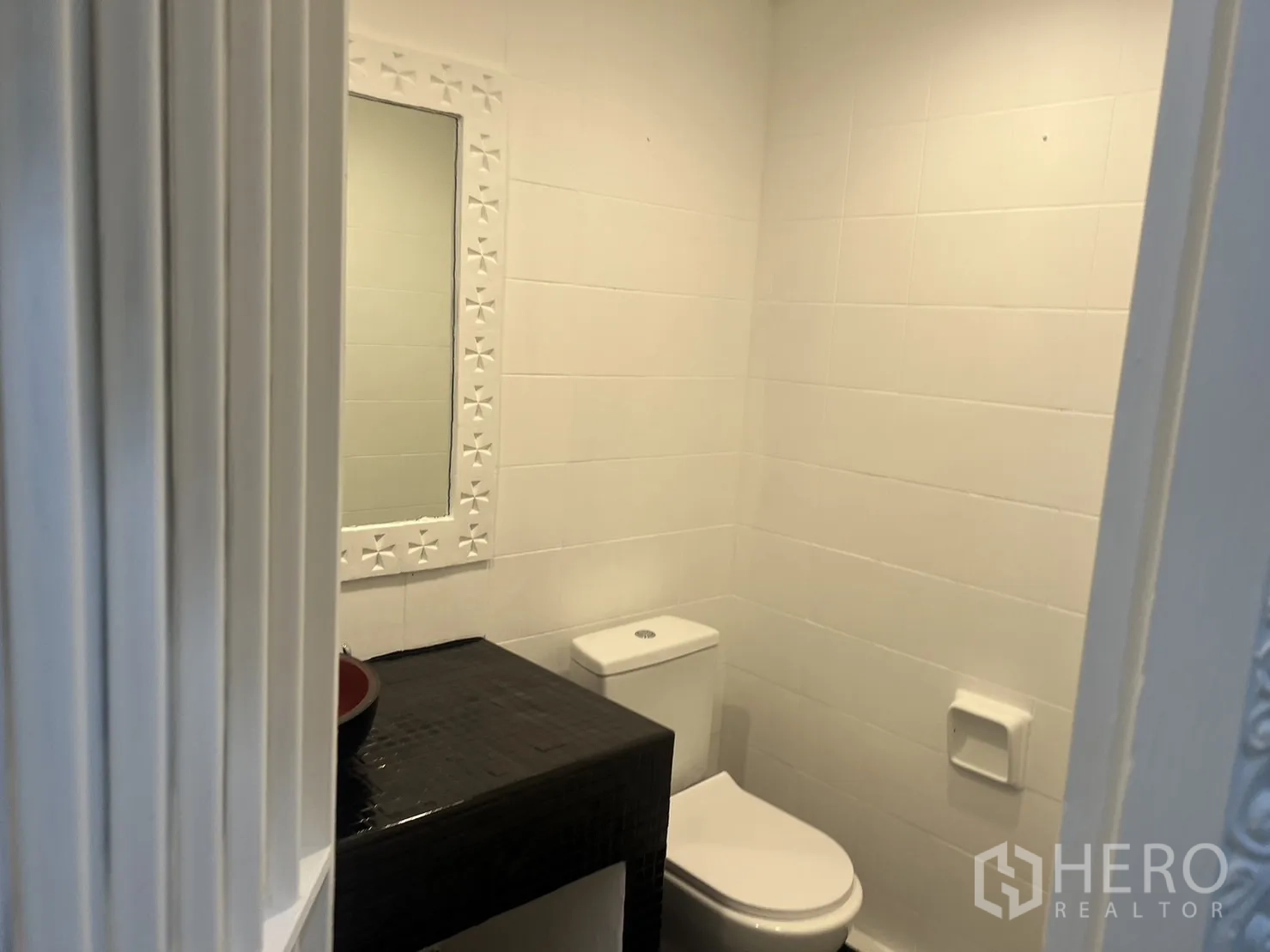 Retail Space for rent in Khlong Toei, Bangkok - Modern restroom with white tiles, framed mirror and toilet.