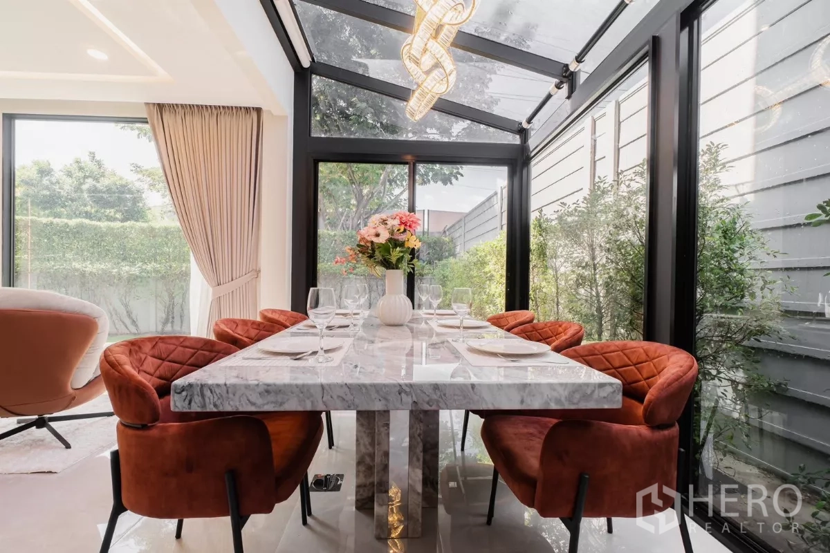 Detached House for rent or sale in Prawet, Bangkok - Sunlit dining room with crystal chandelier, glass walls and garden outlook