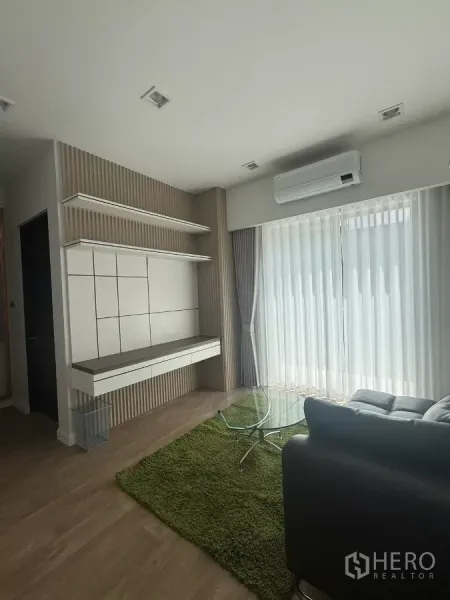 Detached House for rent in Lat Krabang, Bangkok - Cozy family area with glass coffee table, green rug, built-in wall shelves and sliding doors.