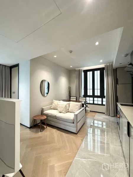 公寓 出租在Watthana, Bangkok - 温馨起居区，沙发与用餐角落，落地窗旁的现代小厨房。
