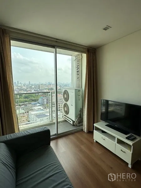 公寓 出售在Watthana, Bangkok - 客厅设电视柜，推拉落地门通往带城市景观的阳台。