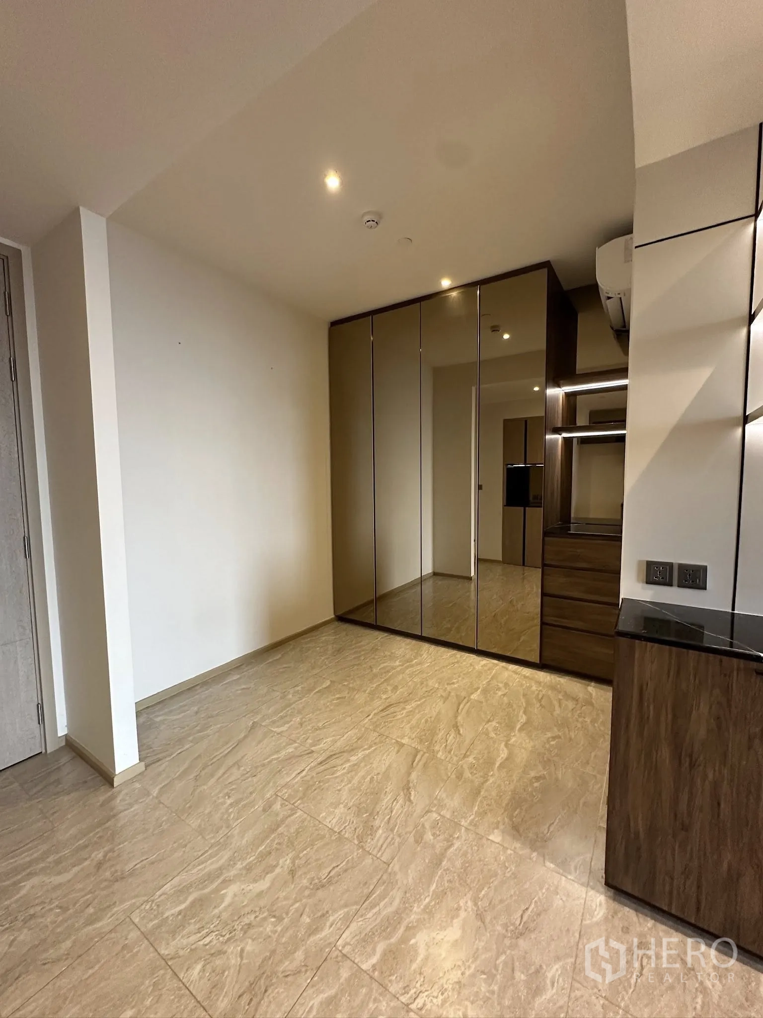 Condominium for sale in Din Daeng, Bangkok - Room with large mirrored wardrobes, drawers, and marble-look tile floor under ceiling spotlights.