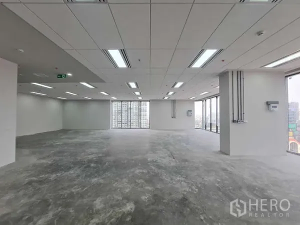 Office Space for rent in Chatuchak, Bangkok - Empty shell office with ceiling‑mounted lighting and tall windows framing city views.