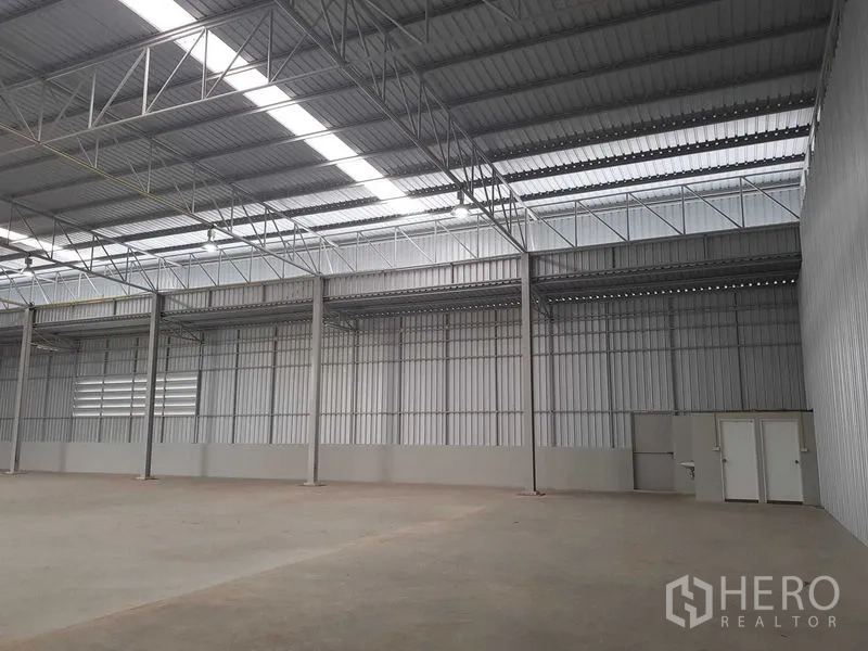 Warehouse for rent in Lat Krabang, Bangkok - Close-up of warehouse wall showing steel columns, skylights and utility room doors on a concrete floor.