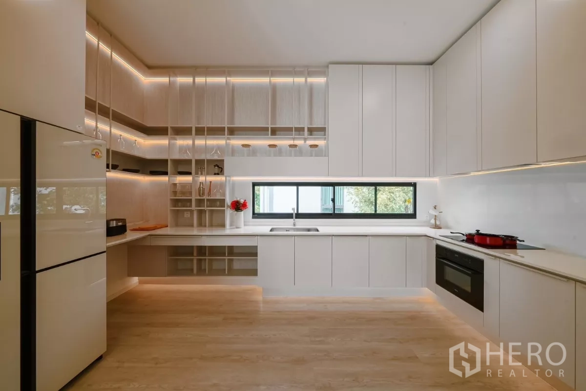 Detached House for rent or sale in Saphan Sung, Bangkok - Full white kitchen with extensive cabinetry, window and integrated appliances.