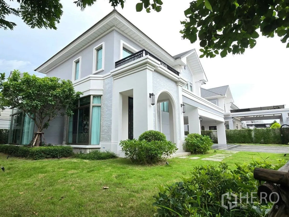 บ้านเดี่ยว for rent or sale in Bang Phli, Samut Prakan - ภายนอกบ้านเดี่ยวสองชั้น โทนขาว ซุ้มโค้ง สนามหญ้า และภูมิทัศน์ร่มรื่น