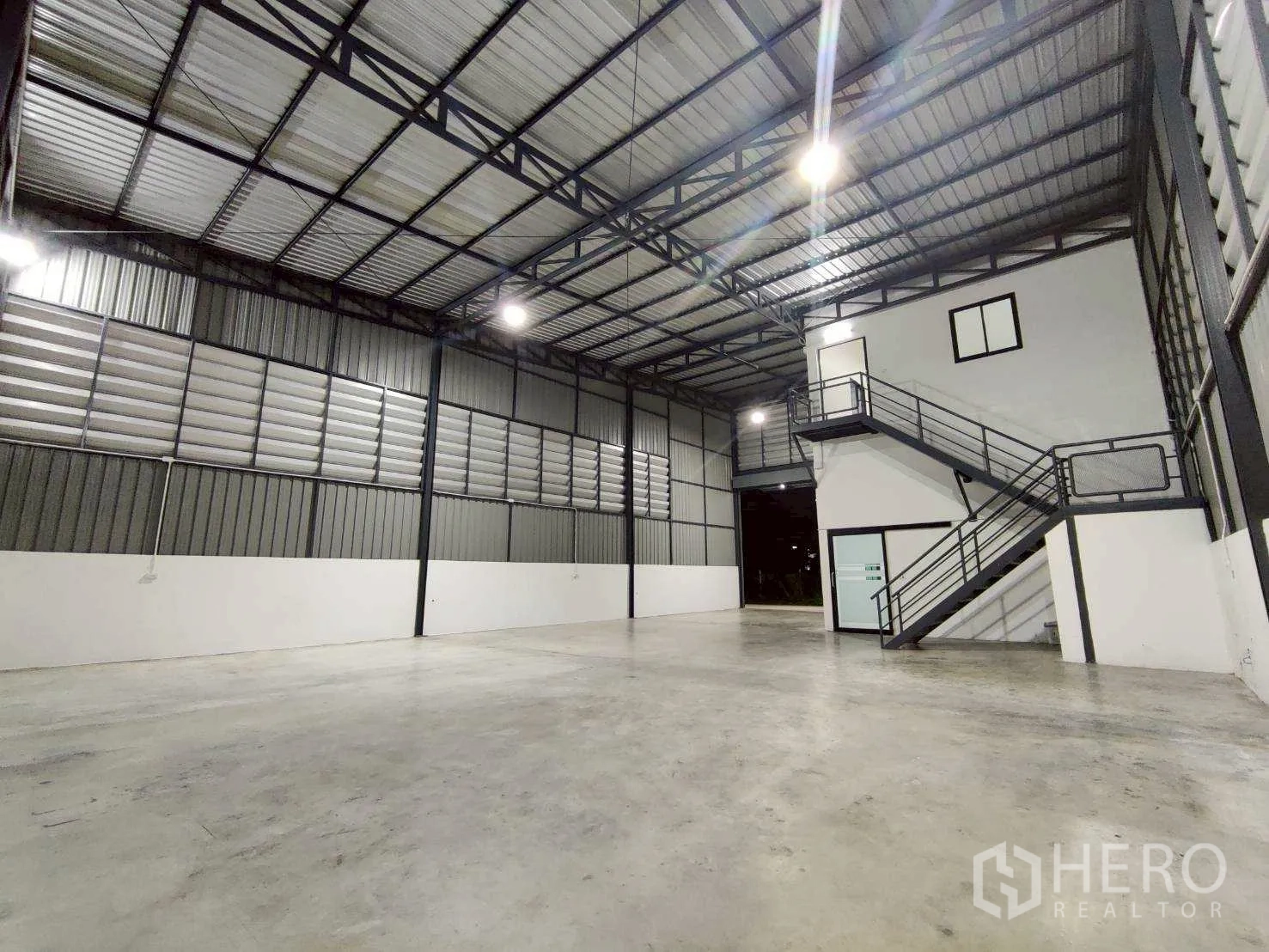 Warehouse for rent in Lam Luk Ka, Pathum Thani - Bright warehouse hall with polished concrete floor and stairway leading to an internal office.
