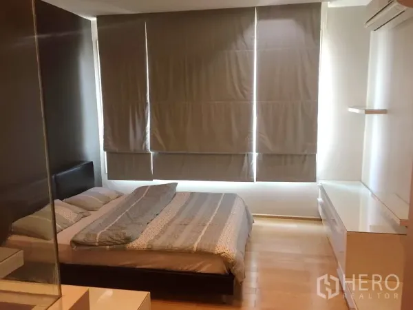 Condominium for rent in Khlong Toei, Bangkok - Spacious bedroom with double bed, blackout blinds, air conditioning, and storage cabinets.
