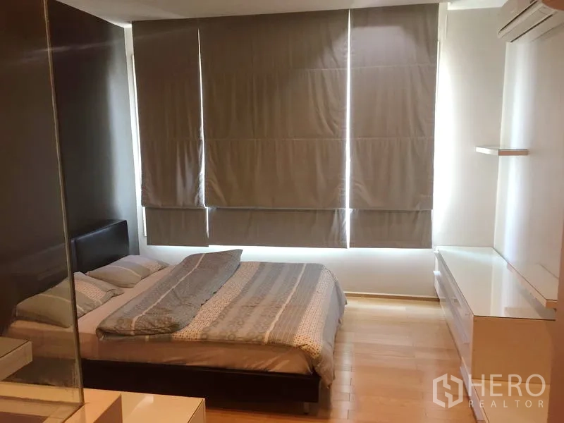 Condominium for rent in Khlong Toei, Bangkok - Spacious bedroom with double bed, blackout blinds, air conditioning, and storage cabinets.