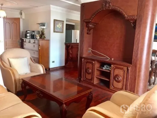 Condominium for rent or sale in Pathum Wan, Bangkok - Living area with classic sofa set, coffee table and ornate built-in TV wall in a Bangkok condo.