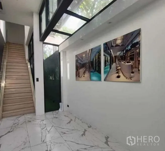 带办公室的家 出租在Suan Luang, Bangkok - 一层大堂，仿大理石地面、玻璃天窗和楼梯，墙上装饰画。