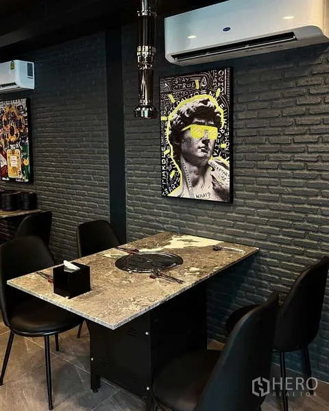 Detached House for rent in Watthana, Bangkok - Contemporary dining corner with stone table, built-in grill, dark brick wall and modern artwork.