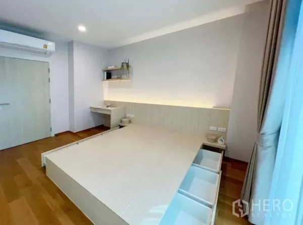 Townhouse for rent or sale in Saphan Sung, Bangkok - Minimal bedroom featuring a platform bed with storage drawers, desk nook and soft cove lighting.