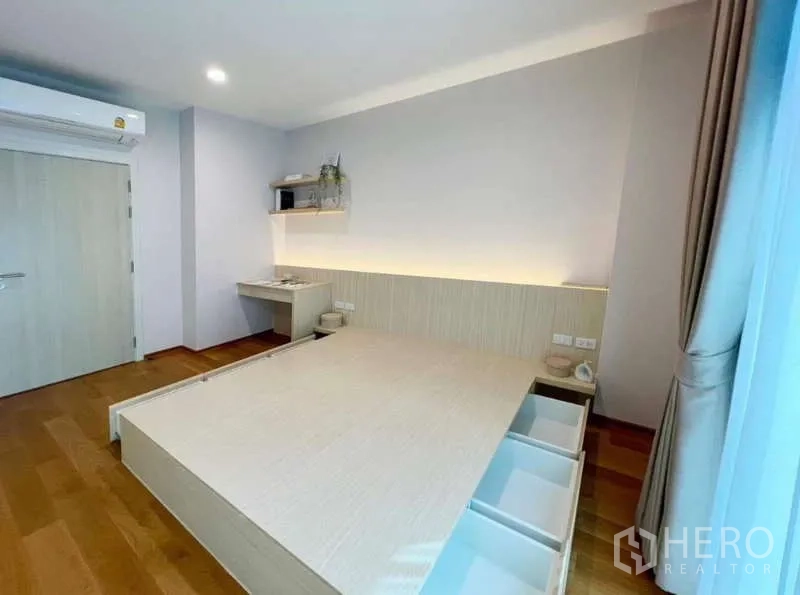 Townhouse for rent or sale in Saphan Sung, Bangkok - Minimal bedroom featuring a platform bed with storage drawers, desk nook and soft cove lighting.