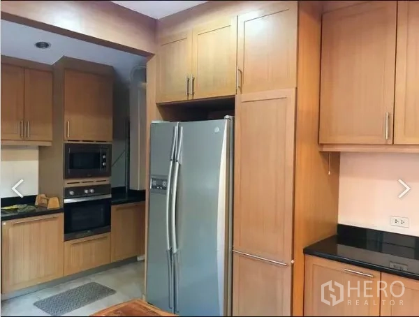 Detached House for sale in Saphan Sung, Bangkok - Kitchen with floor-to-ceiling wooden cabinetry, built-in oven and stainless refrigerator.