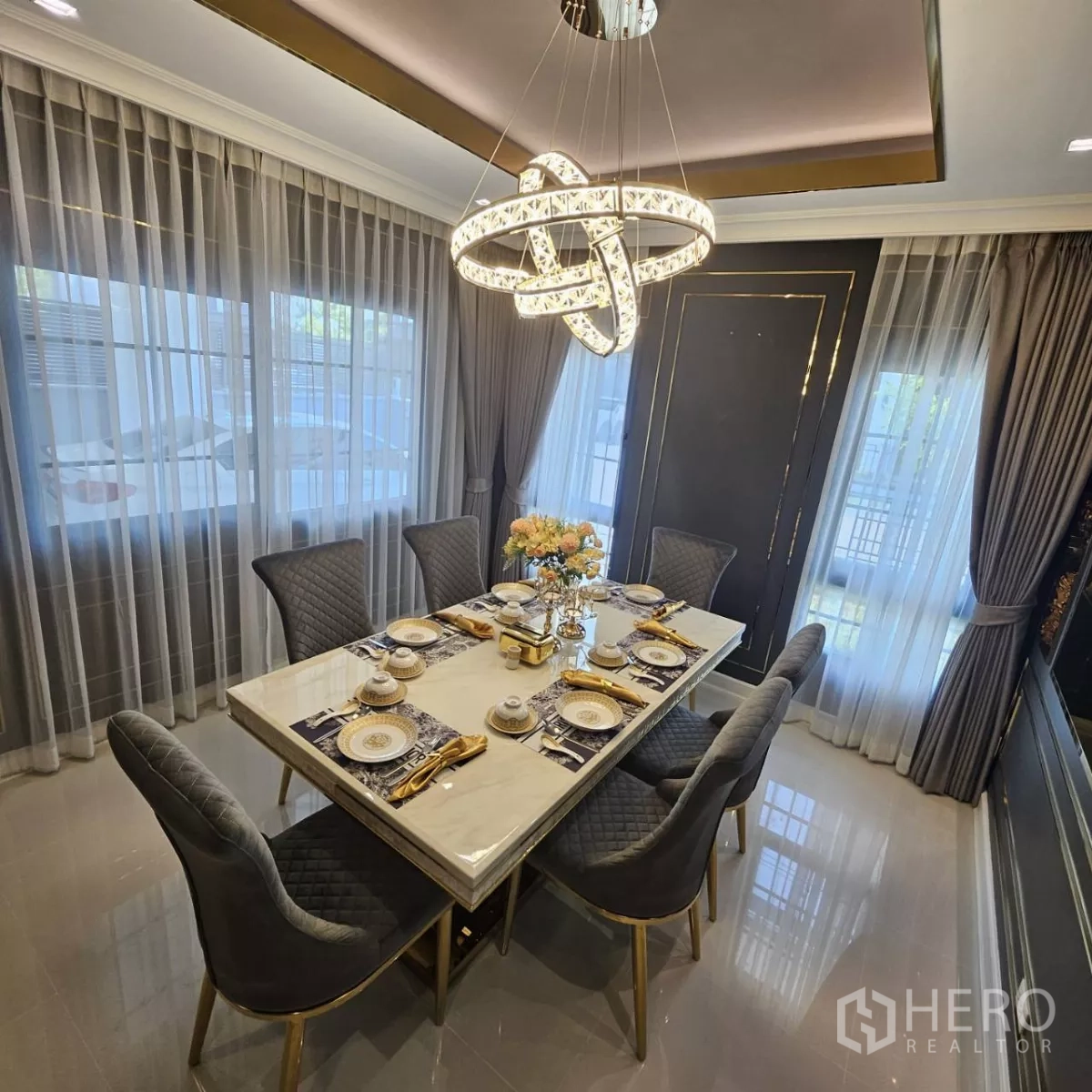 独立式住宅 出租在Bang Phli, Samut Prakan - 精致餐厅，石材餐桌配六把软包椅，环形艺术吊灯与大窗帘。