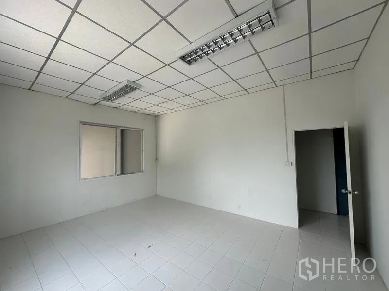 Factory for rent in Bang Bua Thong, Nonthaburi - Clean office room with grid ceiling, lighting and internal window overlooking the production area.