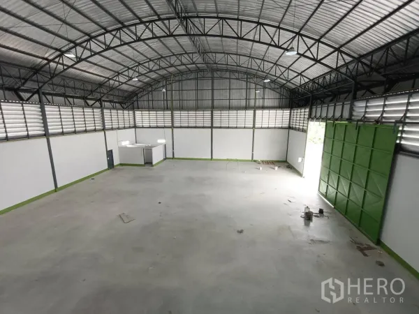 工厂 出租在Lam Luk Ka, Pathum Thani - 宽敞仓库大厅，拱形钢结构屋顶，百叶通风，大型绿色滑门。