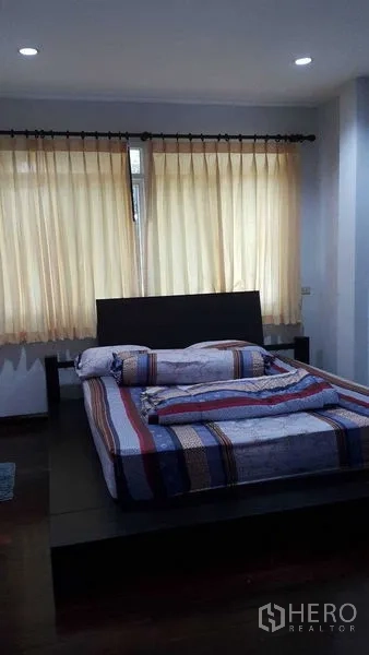บ้าน ขายในBang Na, Bangkok - ห้องนอนพร้อมเตียงแพลตฟอร์ม ผ้าม่านโทนอ่อน และไฟดาวน์ไลท์