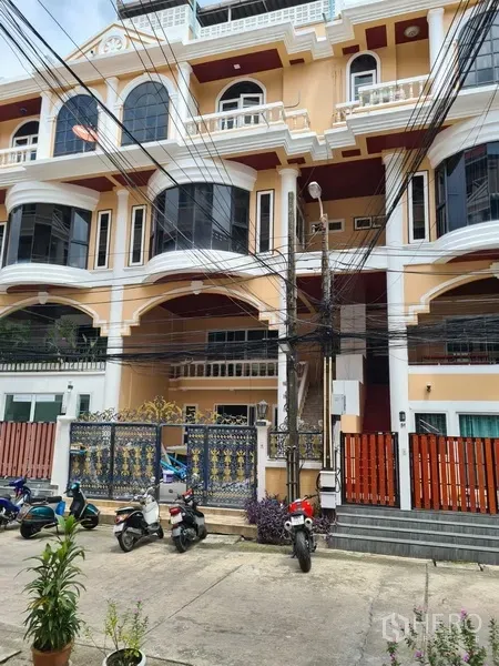 Townhouse for rent in Khlong Toei, Bangkok - Multi-storey townhouse exterior with cream facade, arched balconies and wrought-iron gate near BTS Thong Lo.