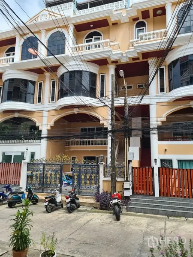 联排别墅 出租在Khlong Toei, Bangkok - 多层联排别墅外观，奶油色立面、拱形阳台与铁艺大门，靠近BTS通罗站