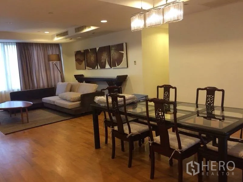 Condominium for rent in Watthana, Bangkok - Open-plan living and dining area with glass-top dining table, pendant lights and sofa lounge.