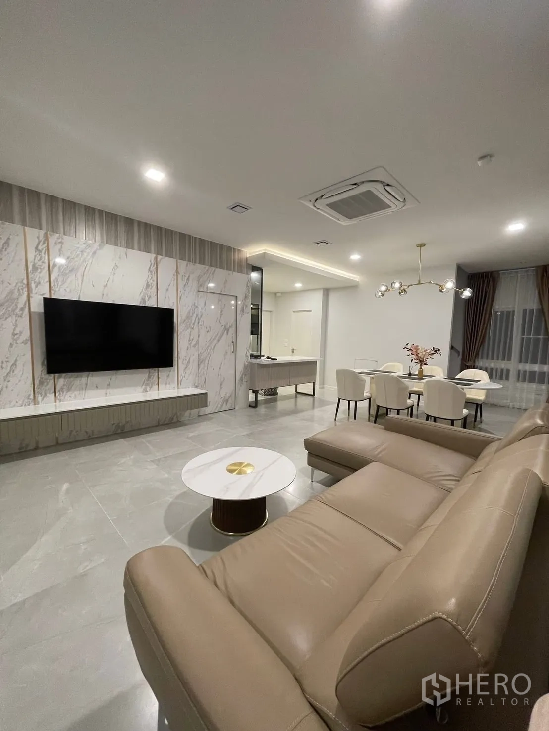 独栋房屋 for rent in Prawet, Bangkok - 开放式客厅，带大理石电视背景墙、L型沙发和餐区。