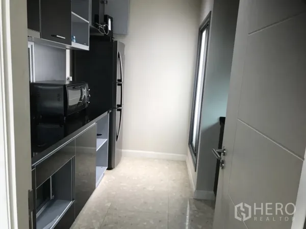 Condominium for rent in Khlong Toei, Bangkok - Separate modern kitchen with glossy black cabinetry, countertop appliances and a tall fridge.