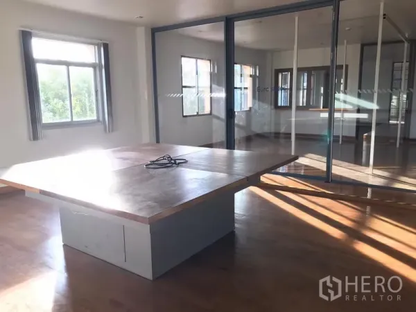 Factory for rent in Mueang Samut Prakan, Samut Prakan - Glass-partition meeting room with a large built-in table and wood flooring.