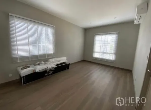 Detached House for rent - Bright empty bedroom with wood flooring, two windows with blinds, and a wall air conditioner.