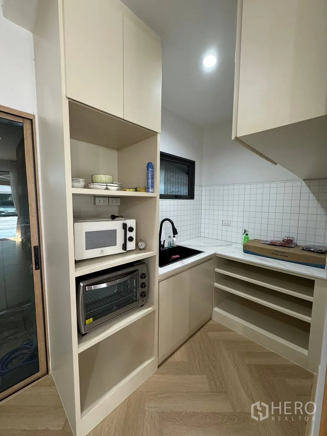 Townhouse for rent in Saphan Sung, Bangkok - Built-in kitchenette with microwave, oven, black sink and shelves.