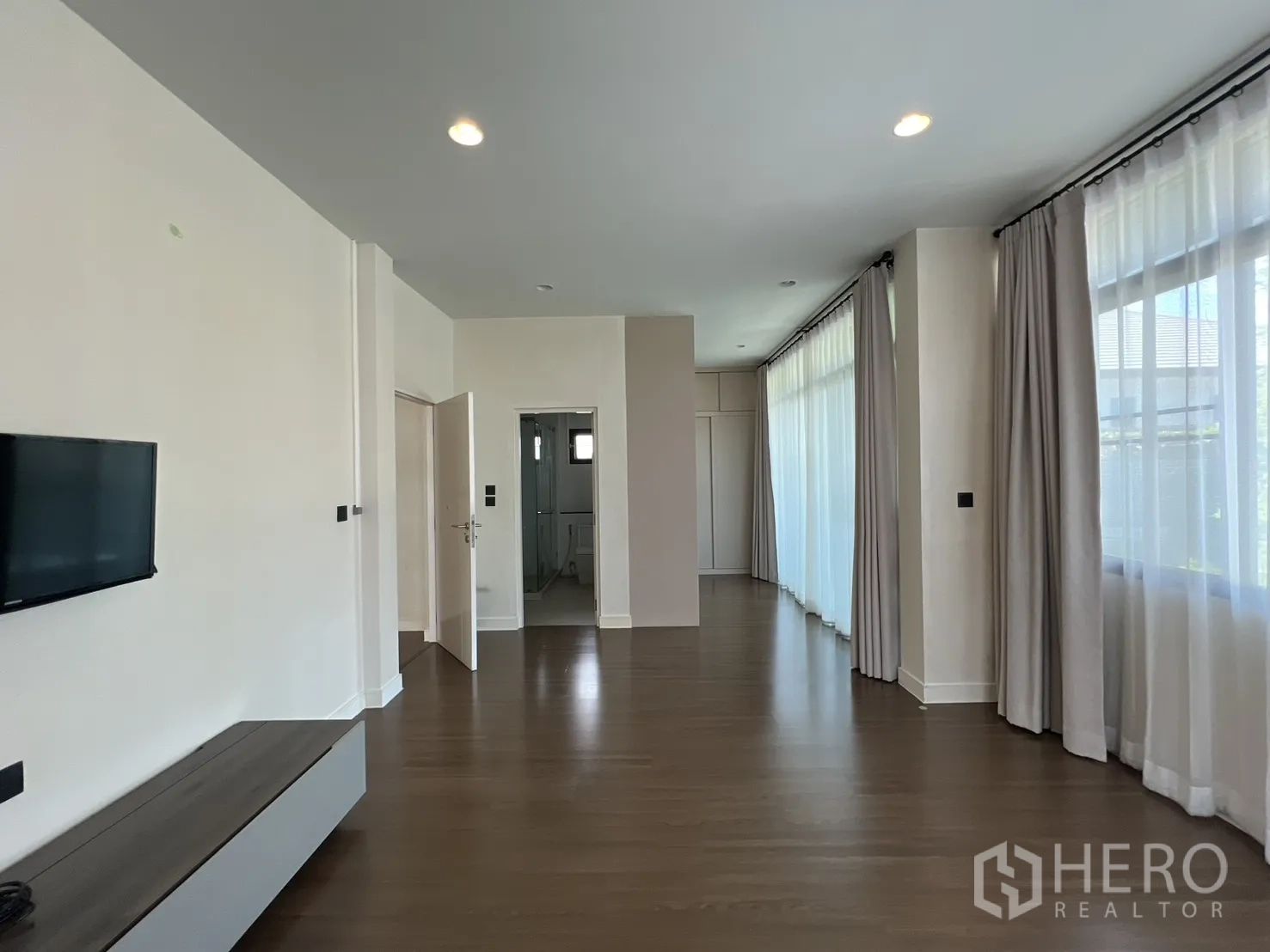 Detached House for sale in Bang Kapi, Bangkok - Master suite with wall-mounted TV and doorway to ensuite bathroom.
