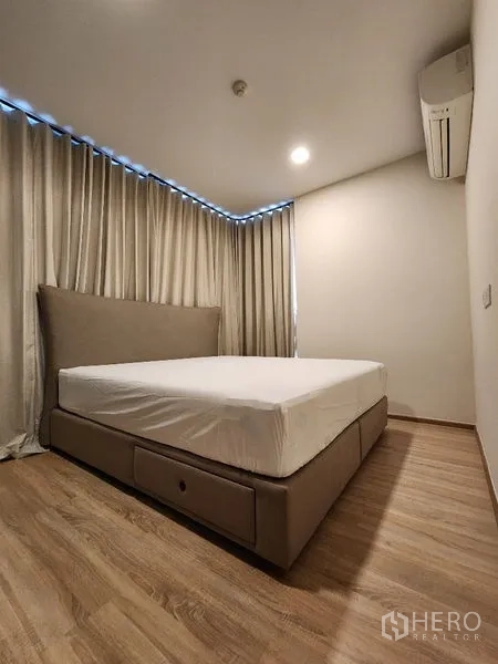 公寓 出租在Khlong Toei, Bangkok - 主卧配大床，转角窗与窗帘，墙挂空调。