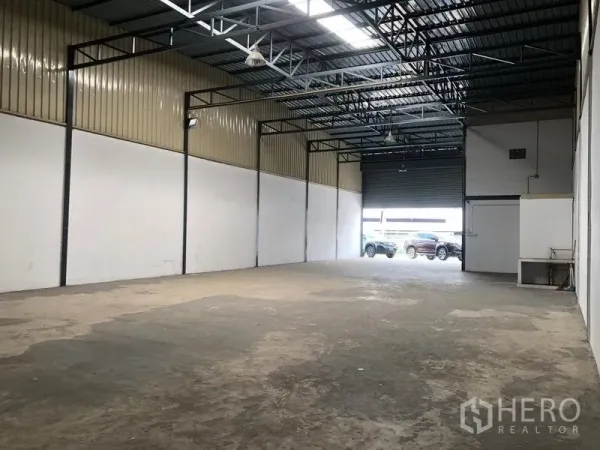 货栈 出租在Pak Kret, Nonthaburi - 朝向卷闸门的内景，外侧可见停车与装卸区域。