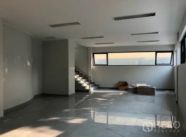 Office Space for rent in Khlong Toei, Bangkok - Open-plan office interior with polished stone flooring, a staircase, and long horizontal windows.