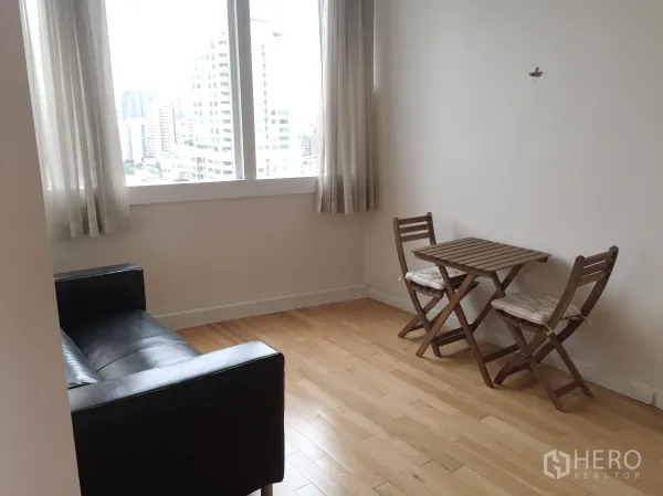 Condominium for rent in Khlong Toei, Bangkok - Cozy nook with a small dining table beside large windows facing the Sukhumvit skyline.