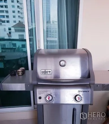 公寓 出租在Watthana, Bangkok - 私密阳台配不锈钢燃气烧烤炉，旁为推拉玻璃门。